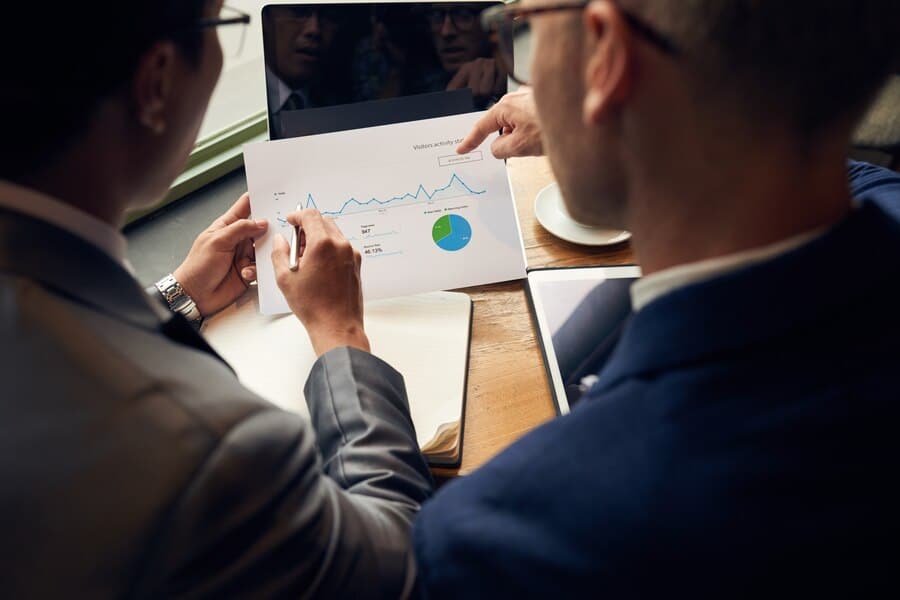 Two colleagues review a printed pie chart together.