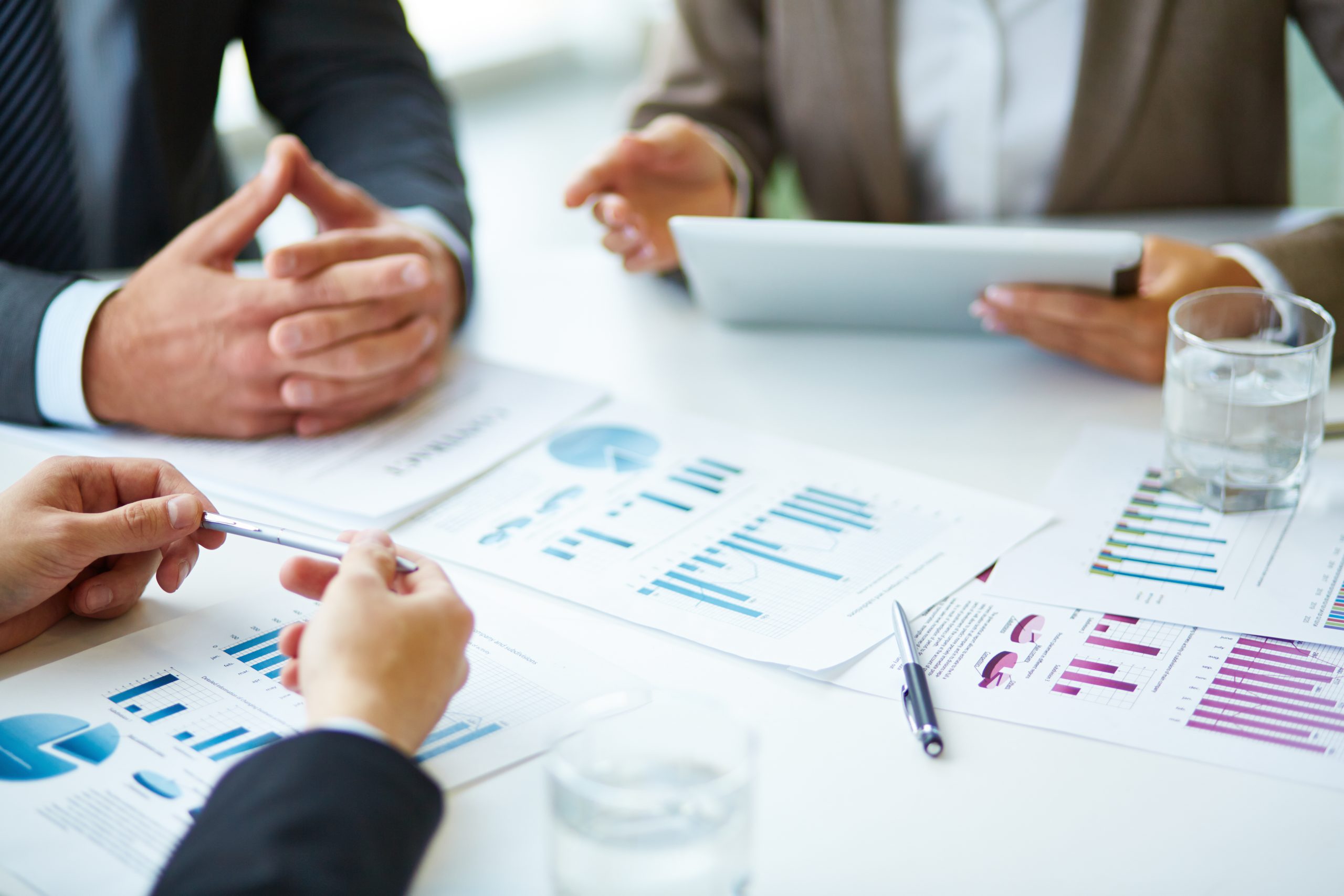 Hands and printed charts spread across a meeting table.