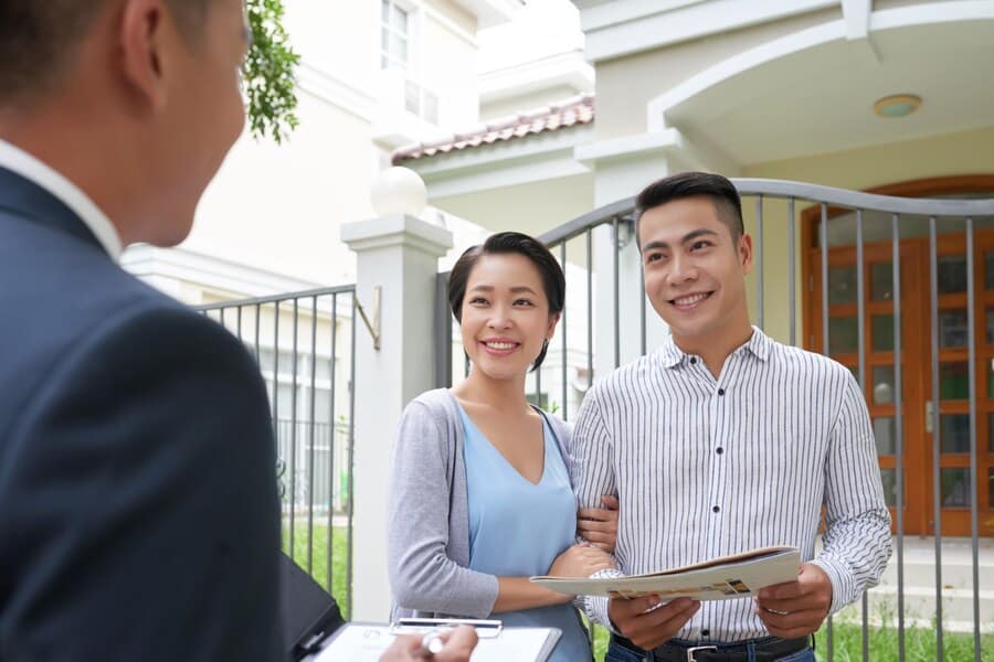 An adviser talking with a couple outside a property.
